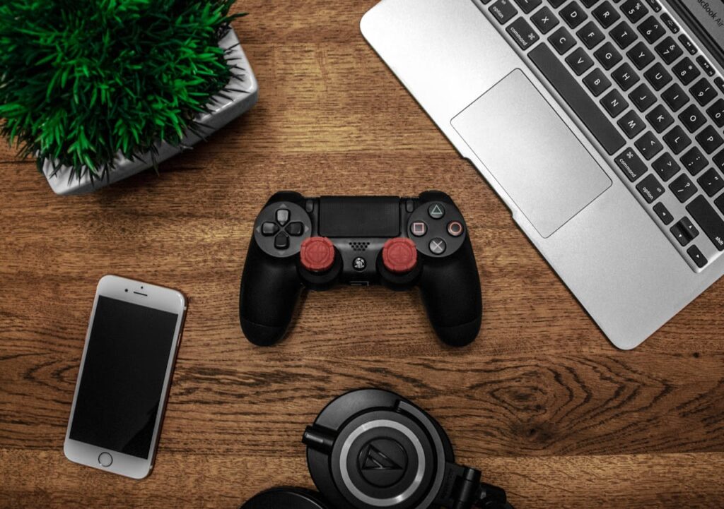 pexels-photo-682933 A flat lay photo showcasing a gaming console, laptop, smartphone, and headphones on a wooden tabletop.